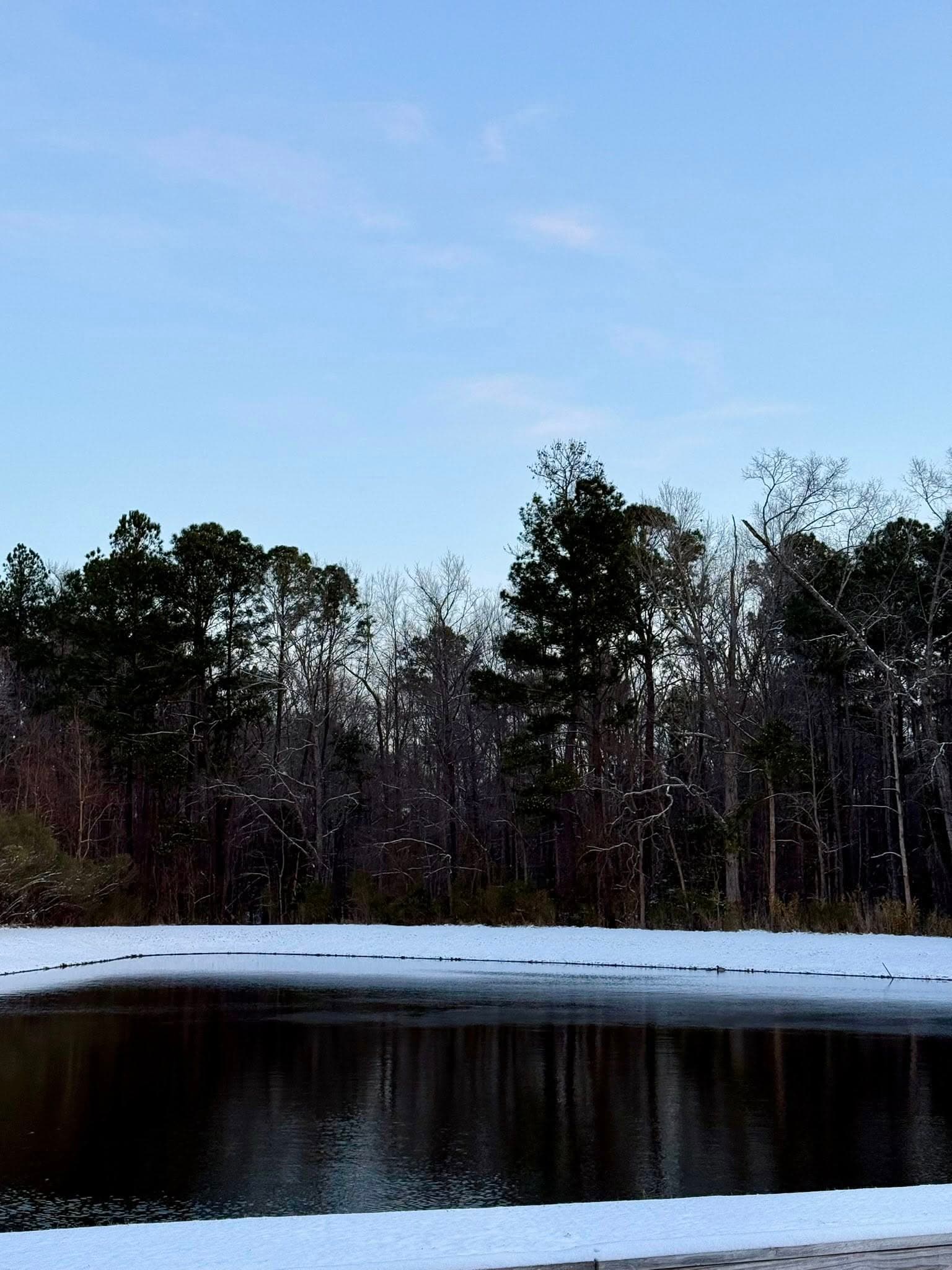 Strawberry Station pond ringed with snow on a clear winter morning
